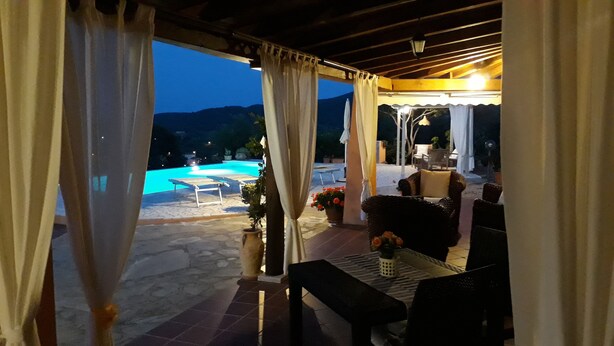An outdoor patio area with a pool, seating, and a view of the mountains at dusk. - Li Muntigeddi (San Teodoro)