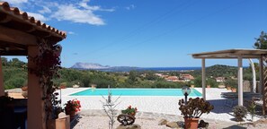 A pool with a clear view of mountains and the sea.