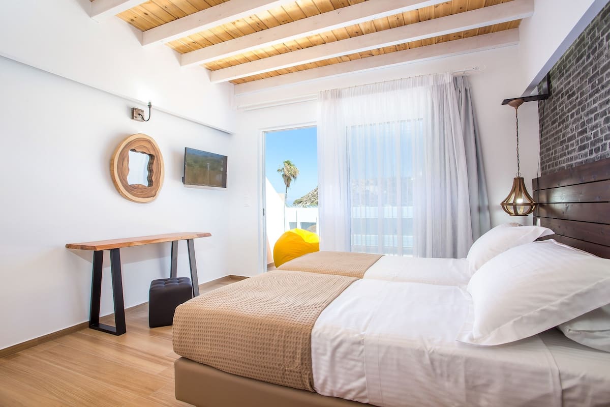 A bedroom with a bed, a desk, and a window with curtains.