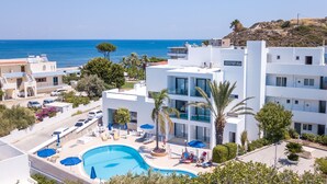 A modern hotel with a pool, multiple balconies, and a view of the sea. - Moscha Hotel (Rhodes)