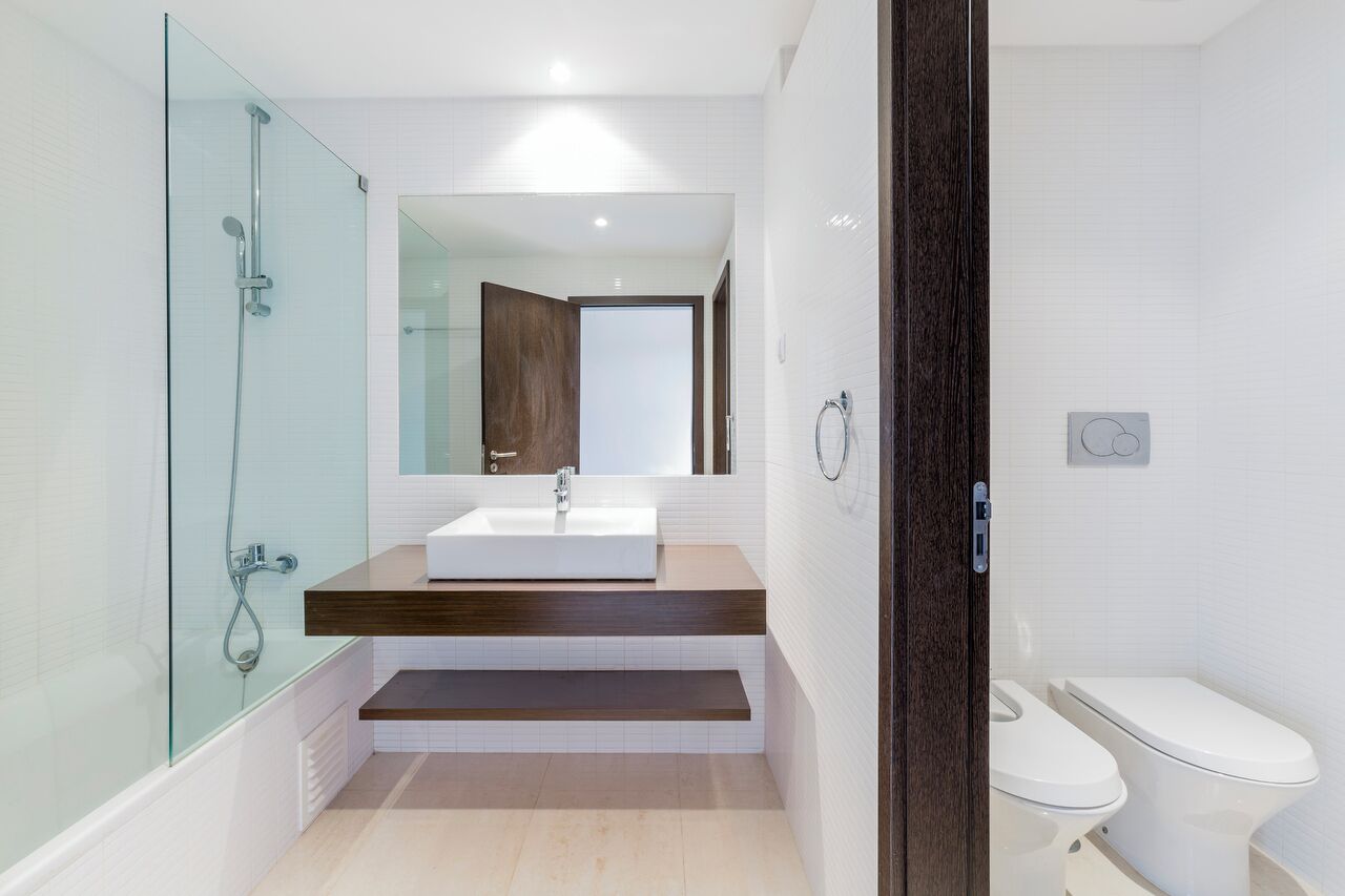 A modern bathroom with a glass-enclosed shower, a white sink, and a wooden vanity.