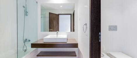 A modern bathroom with a glass-enclosed shower, a white sink, and a wooden vanity.