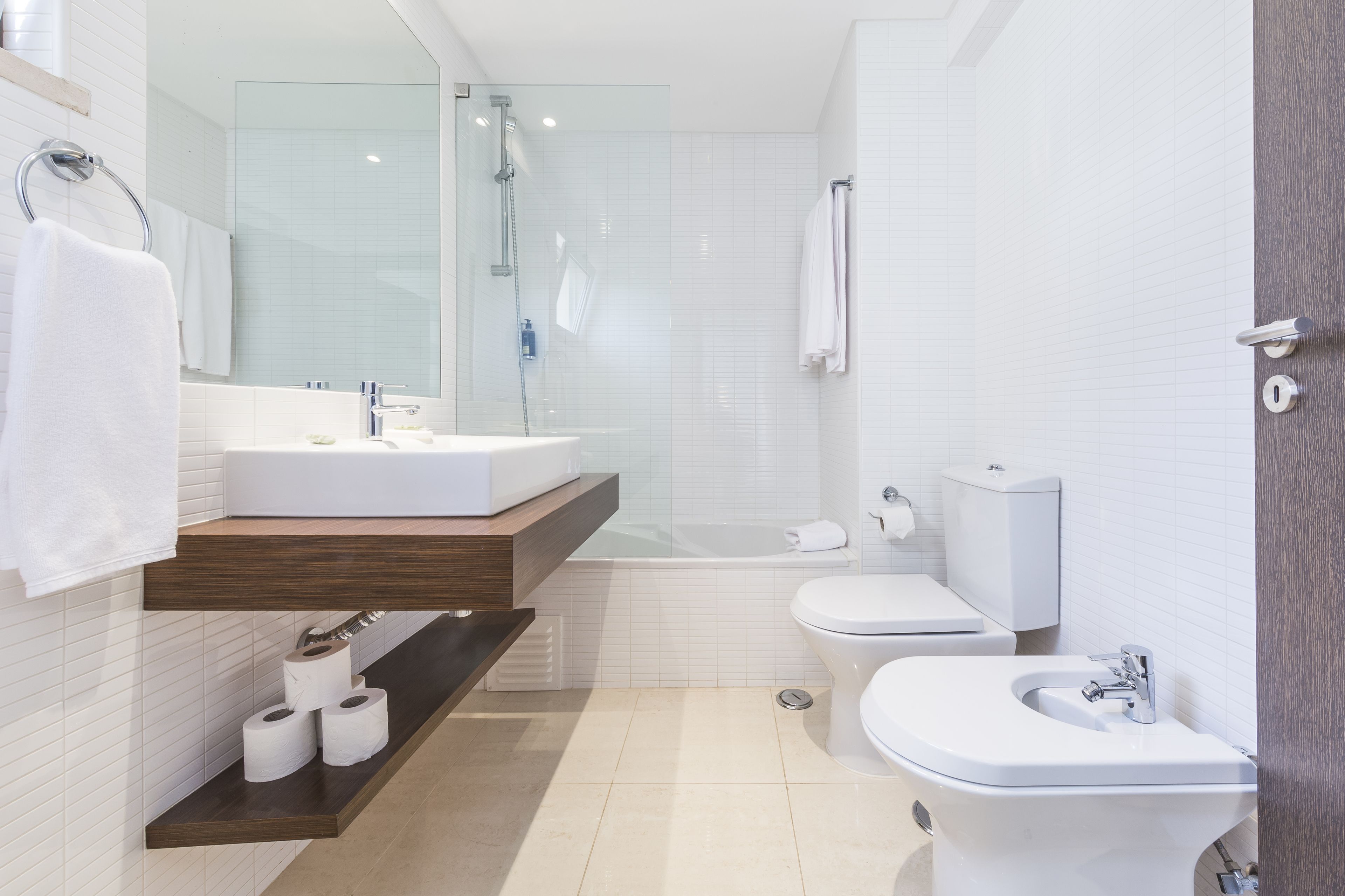 Un baño moderno con ducha acristalada, lavamanos blanco, inodoro y bidé.