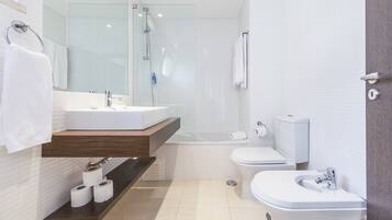 A modern bathroom with a glass-enclosed shower, a white sink, a toilet, and a bidet.