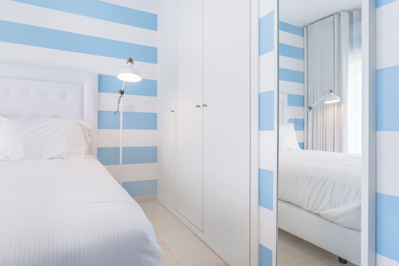 Une chambre d’hôtel avec un lit, une armoire et un miroir.