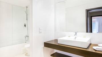 Een moderne badkamer met een witte wasbak, een douchecabine van glas en een houten wastafelmeubel.