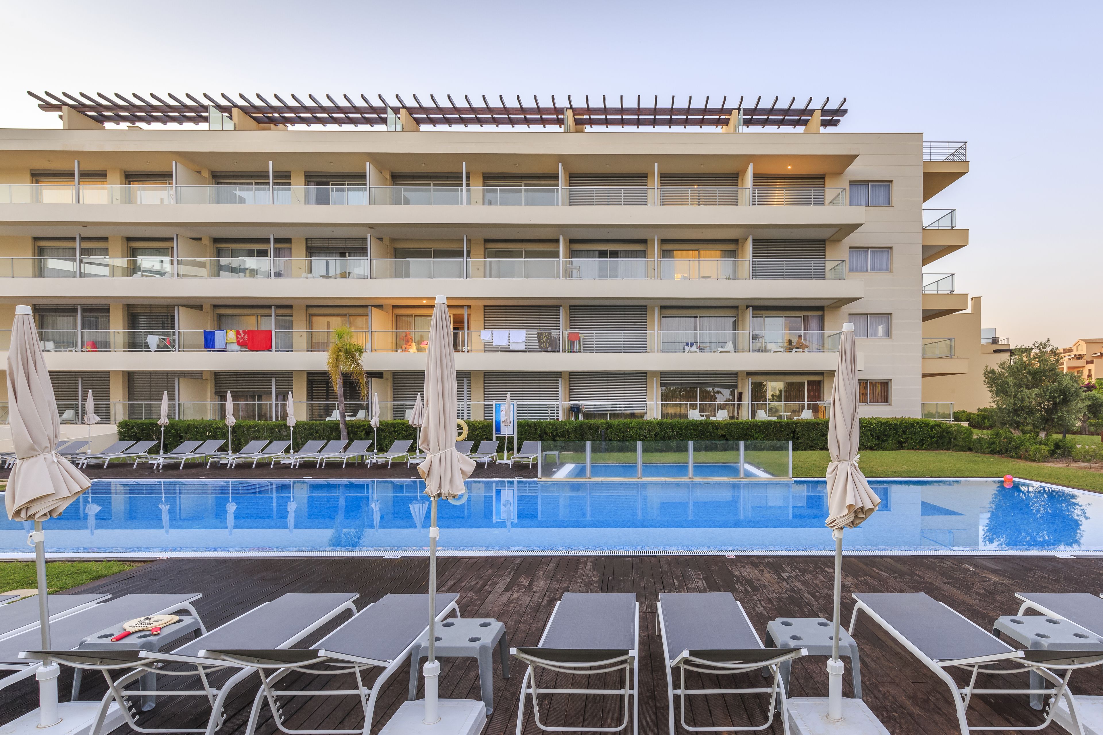 A hotel with a pool area, multiple balconies, and sun loungers.