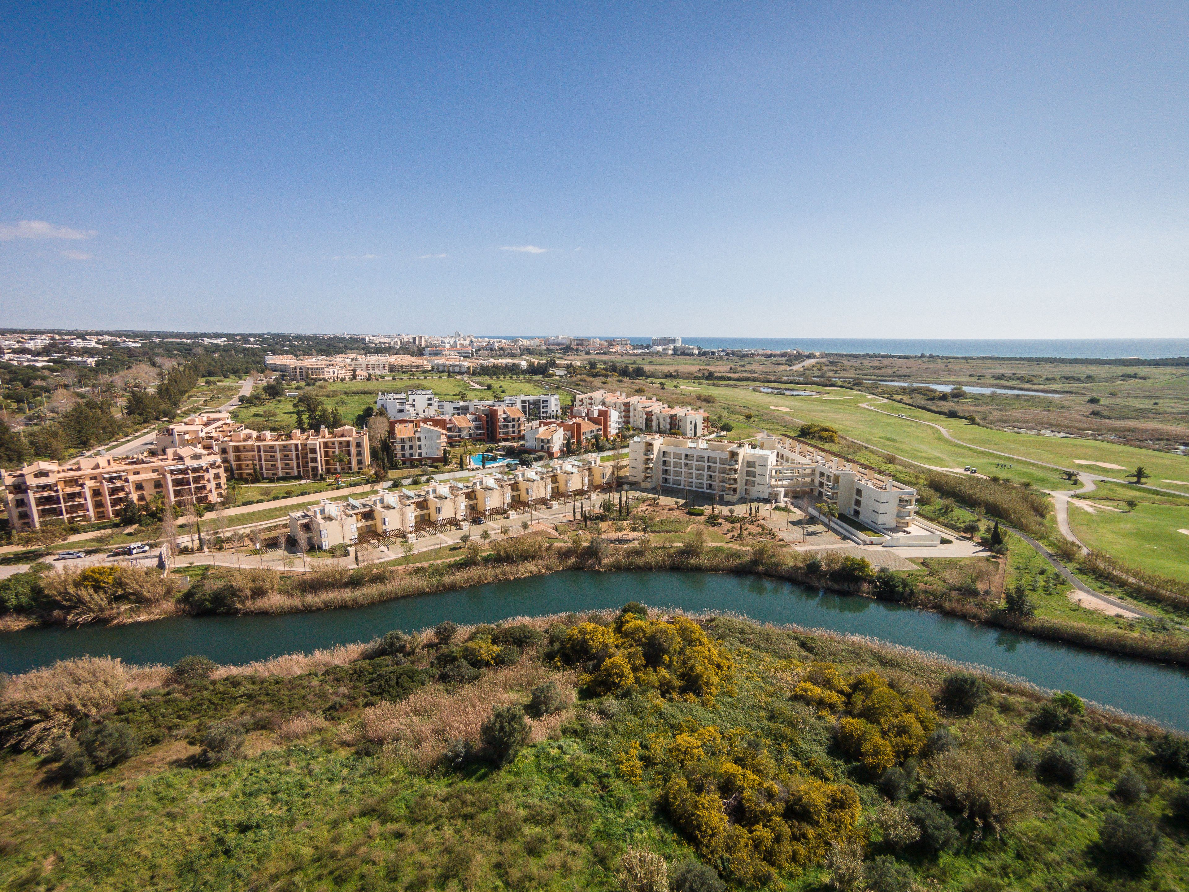 A coastal resort with multiple buildings, a golf course, and a river.