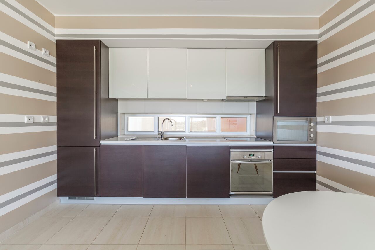 A modern kitchen with dark cabinets, a stainless steel oven, and a microwave.