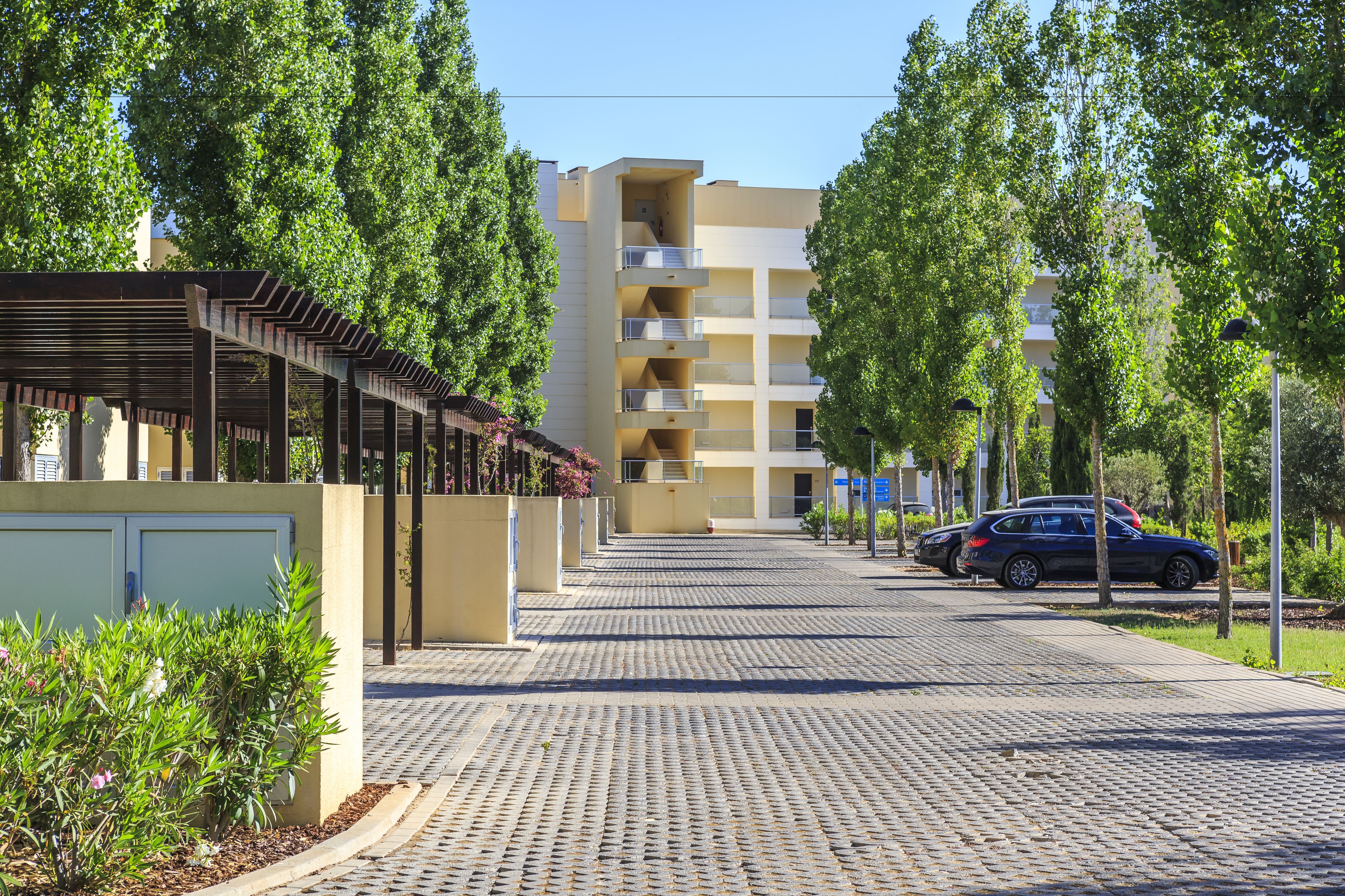 A paved pathway leading to a multi-story building with balconies.