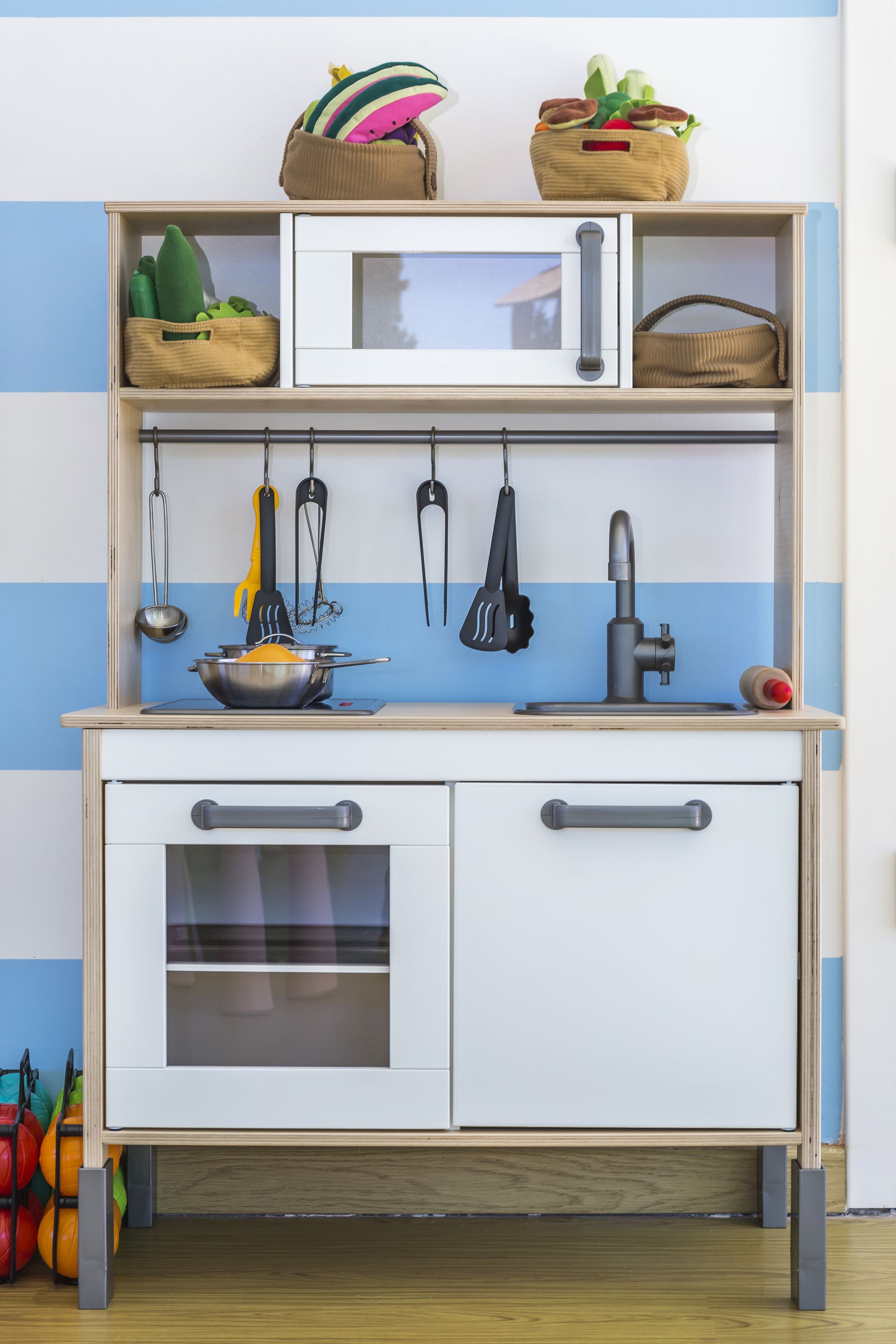 A kitchenette with a microwave, stove, and hanging utensils.