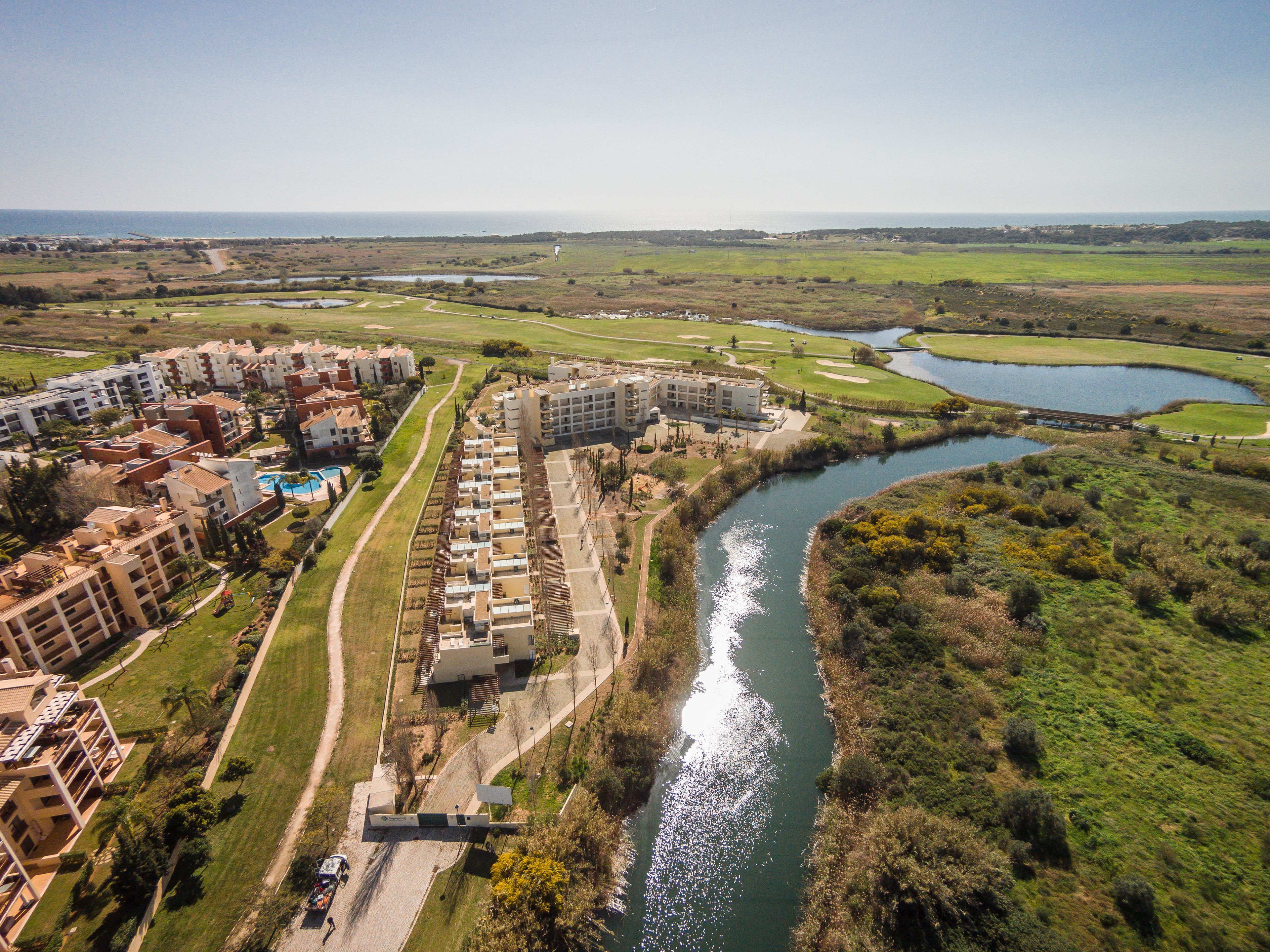 Un hôtel situé au bord de la rivière, composé de plusieurs bâtiments, doté d’une piscine et d’un parcours de golf.