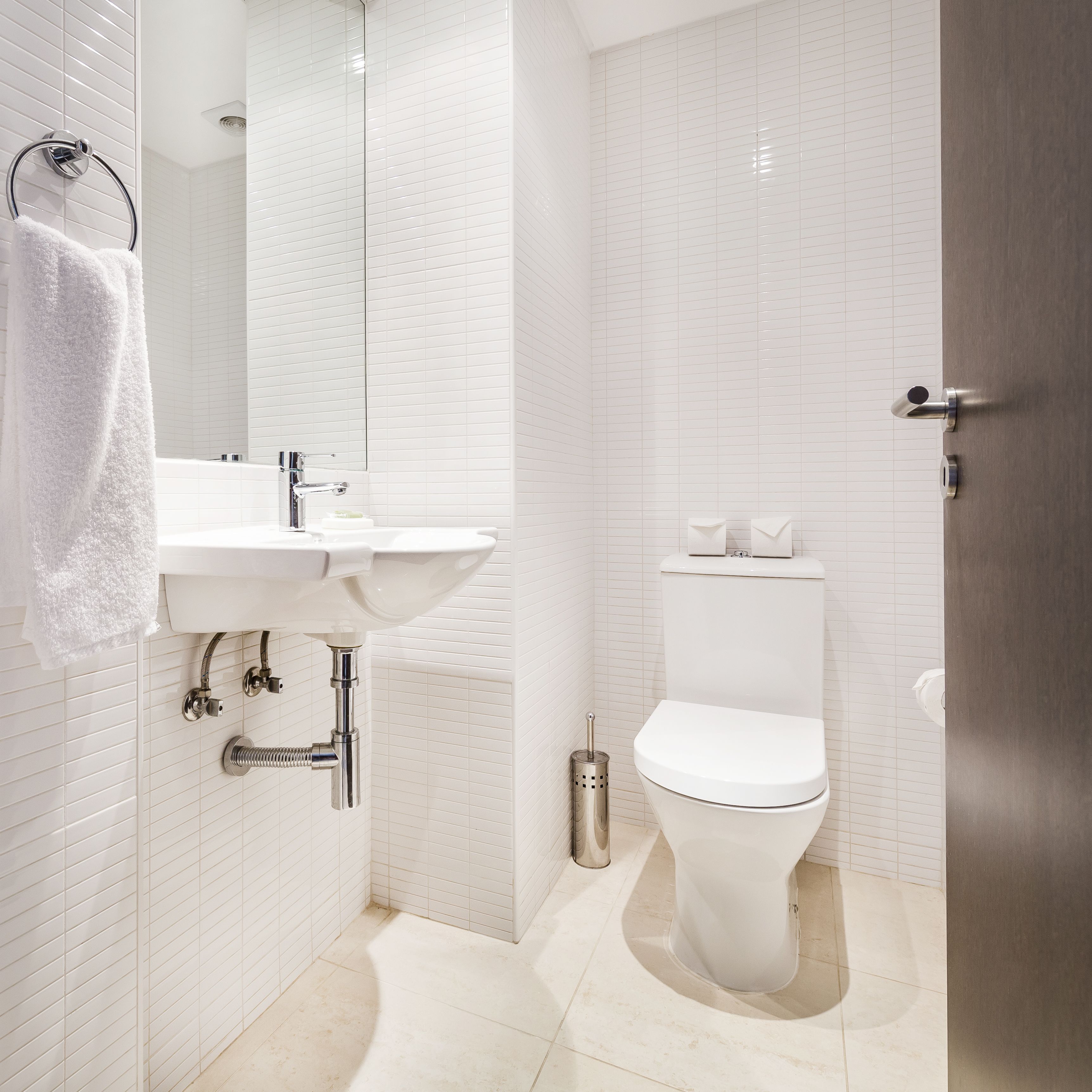 Un baño moderno con lavamanos blanco, grifo cromado y inodoro.