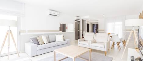 A modern living room with a sofa, armchairs, a coffee table, and a TV.