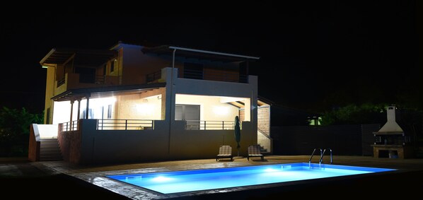 Ein modernes, zweistöckiges Haus mit Swimmingpool, Außenbereich und Grillplatz.