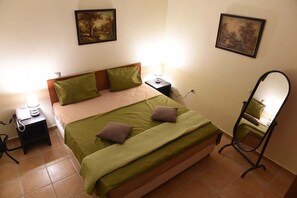 Ein Schlafzimmer mit einem Bett, zwei Nachttischen, einem Spiegel und zwei Wandbildern.