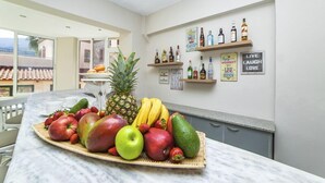 A kitchen with a marble countertop, a fruit platter, and shelves with liquor bottles and motivational posters. - Malia Central (Hersonissos)