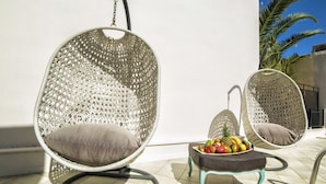 Two hanging chairs with cushions, a small table with fruit, and a tiled floor. - Malia Central (Hersonissos)