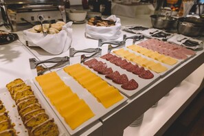 A buffet with various food items including meats, cheeses, and bread. - Dos Reyes Hotel (Mar del Plata)