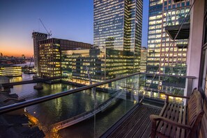 Een moderne stadsgezicht met hoogbouw, een rivier en een voetgangersbrug.