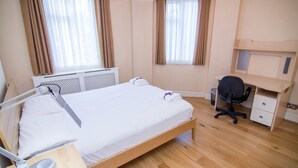 Una habitación de hotel con una cama individual, un escritorio y una silla.