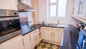 Una cocina moderna con electrodomésticos de acero inoxidable, piso a cuadros y armarios de madera clara.