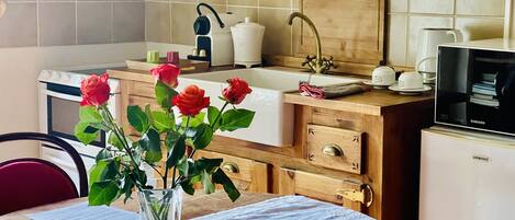 Une cuisine avec un plan de travail en bois, un évier, un four à micro-ondes et un vase rempli de roses posé sur la table.