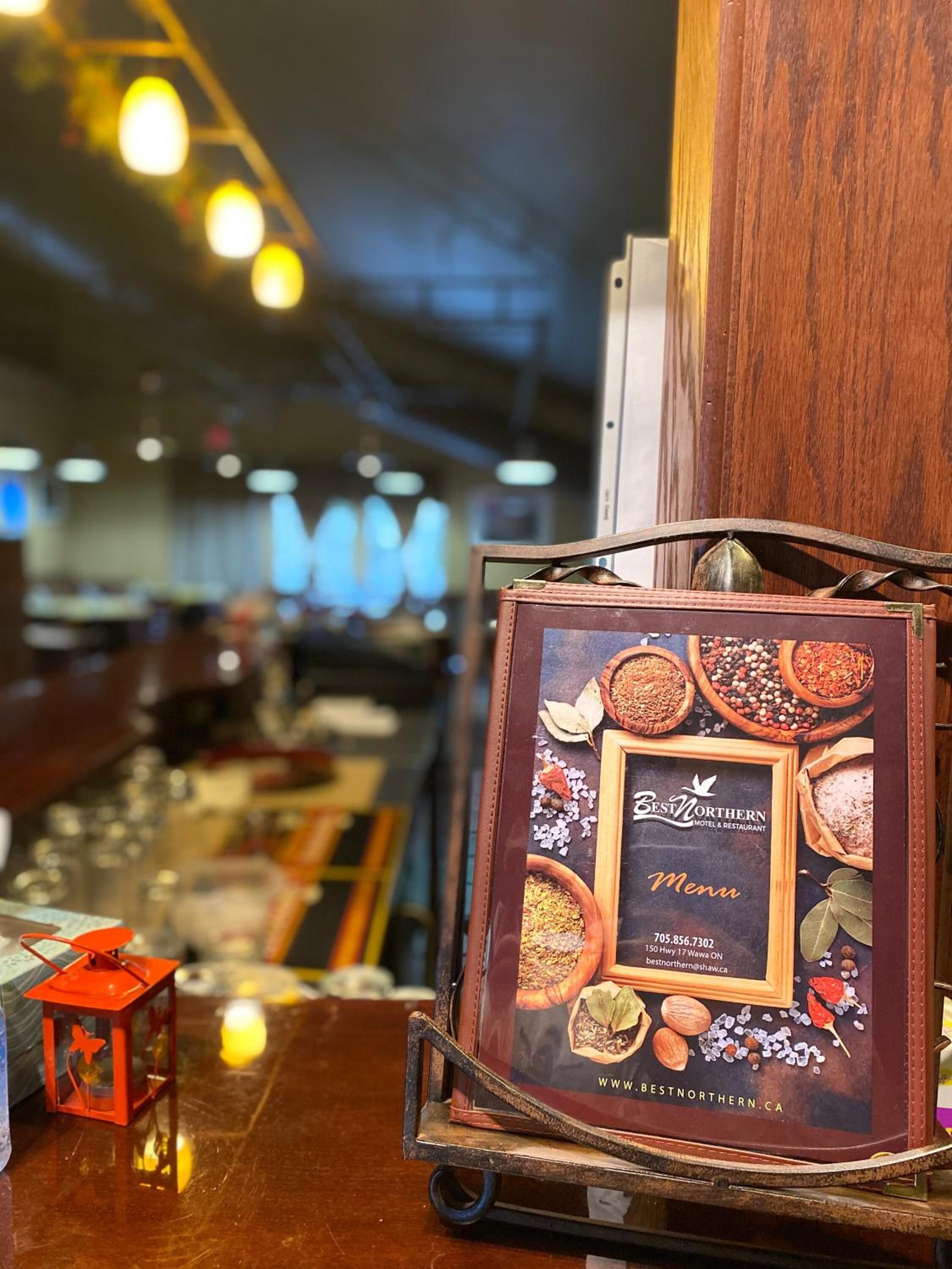 Un présentoir à menu avec une enseigne indiquant « Meilleur hôtel et restaurant du Nord », où sont présentées différentes épices et herbes aromatiques.
