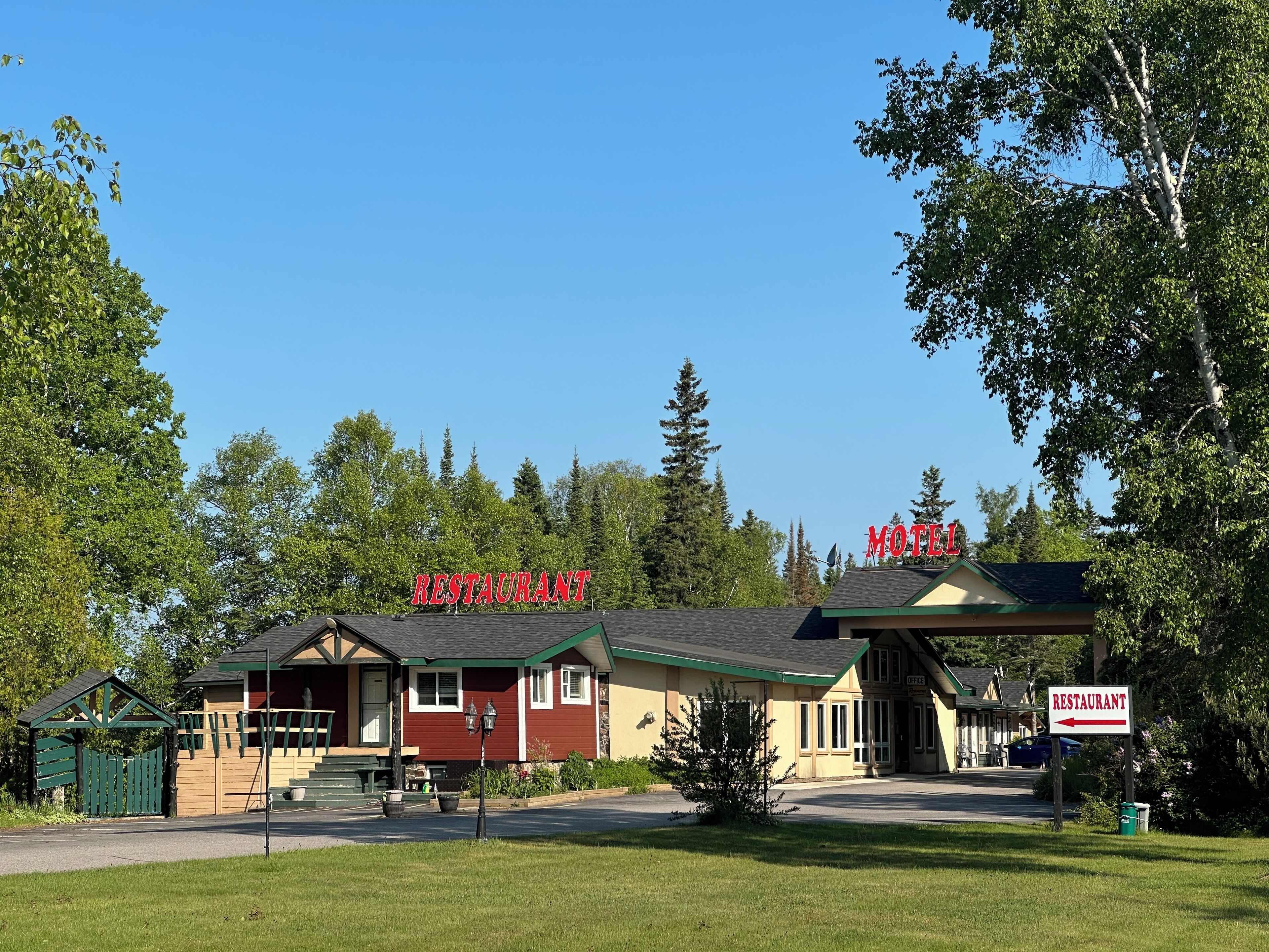 A motel with a red sign, a green entrance, and a small parking area.