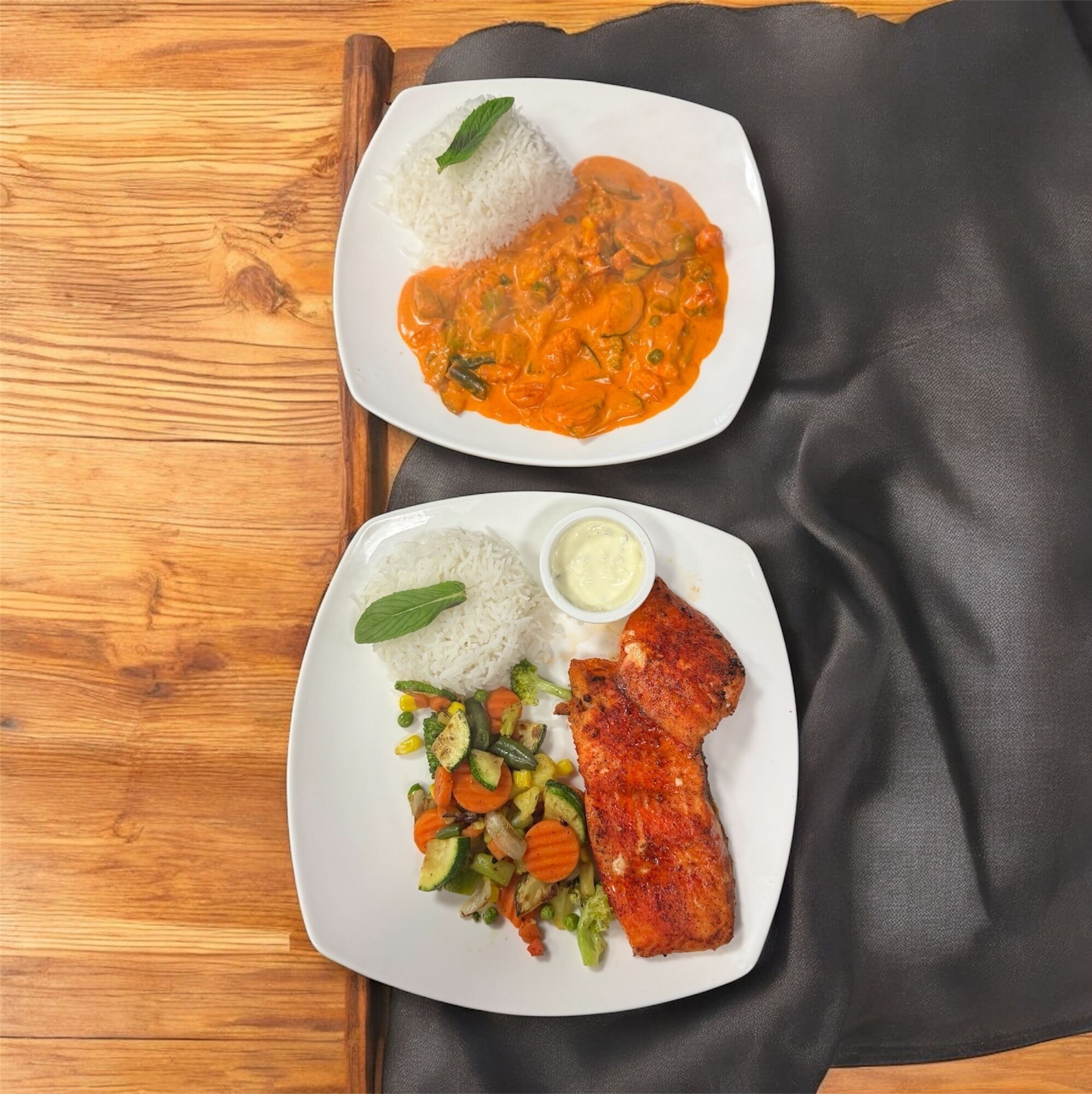 Two plates of food on a wooden table.