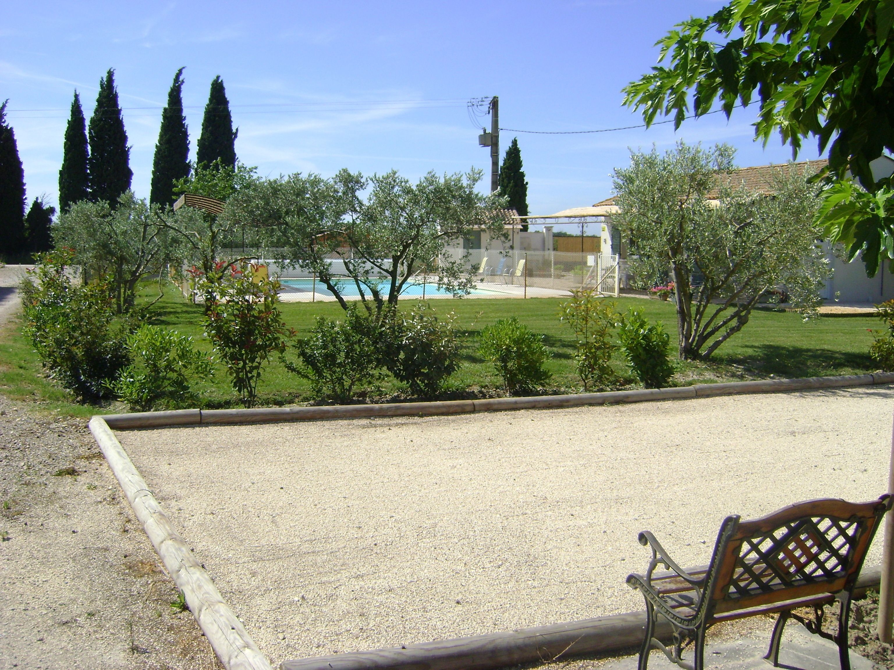 A garden with a pool, a bench, and a fence.