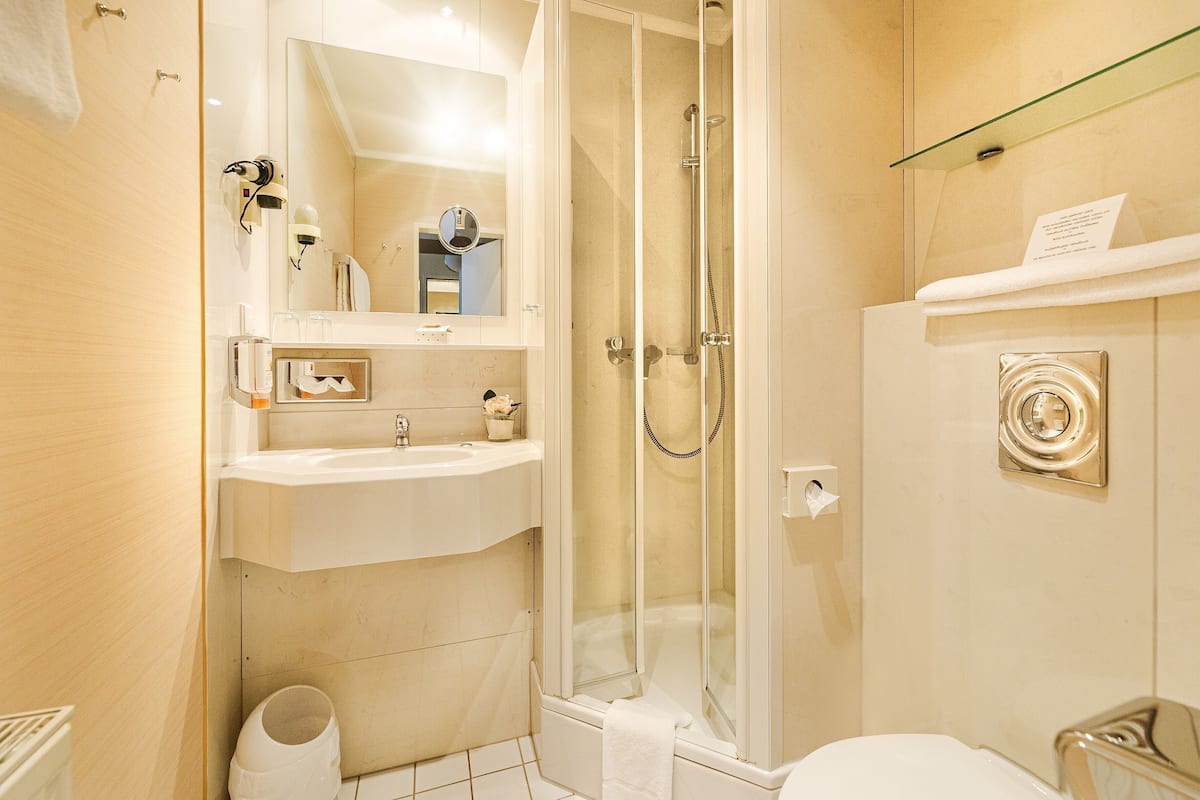 A modern bathroom with a glass-enclosed shower, a sink, and a toilet.
