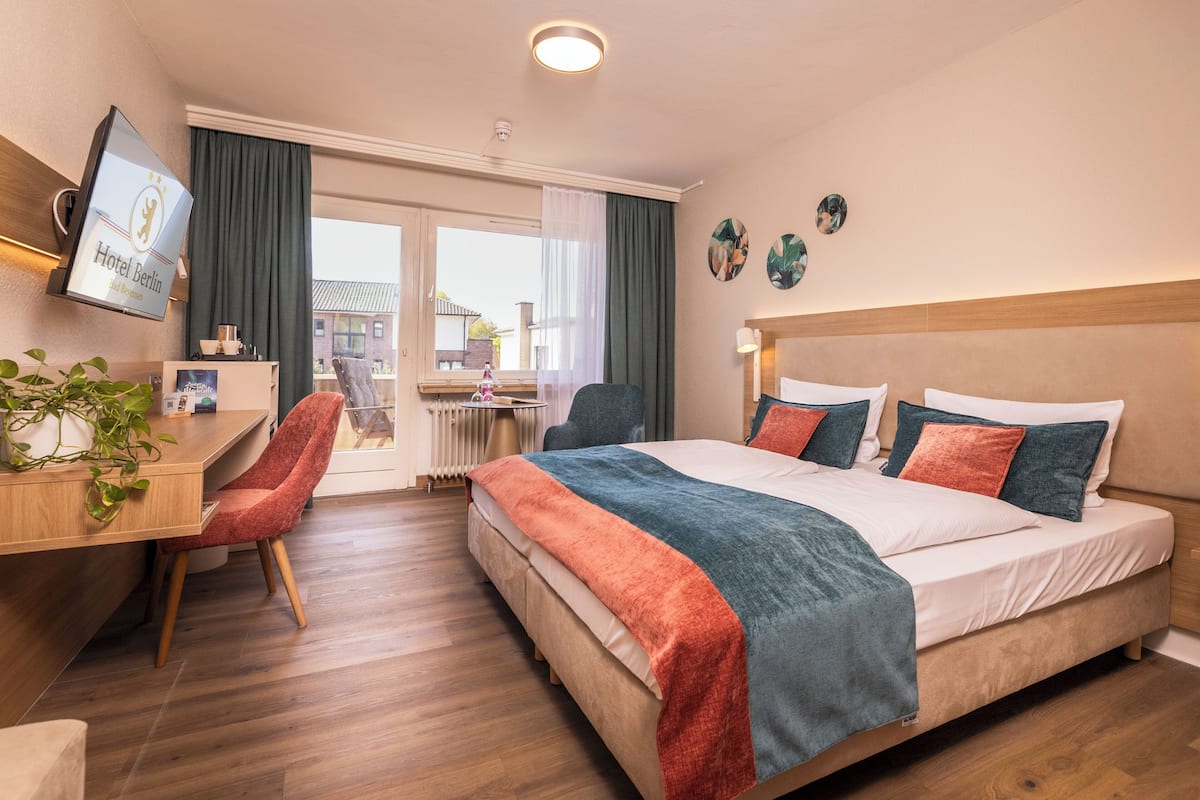 A hotel room with a bed, desk, chair, and a television displaying the hotel name.