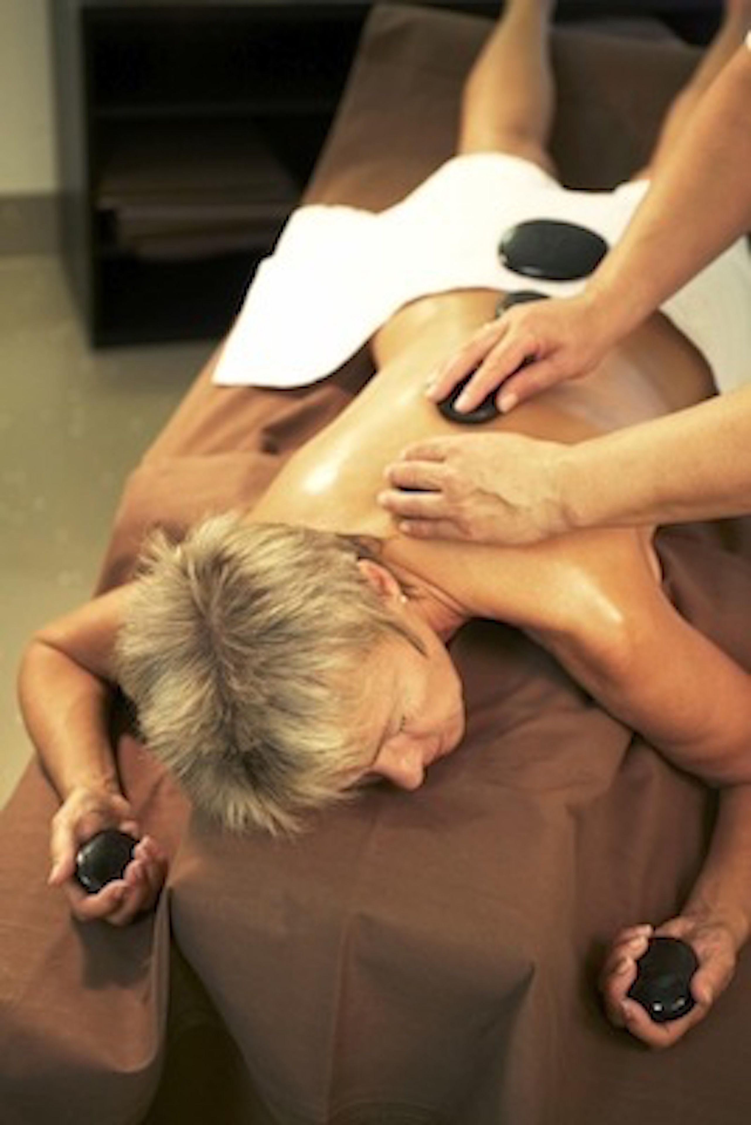 A person receiving a back massage on a massage table.