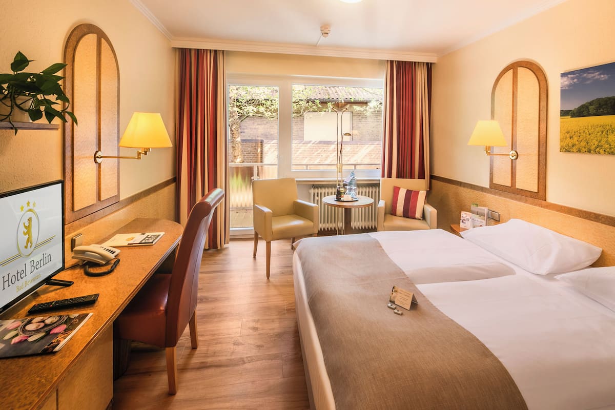 A hotel room with a bed, desk, chair, and a view of the outdoors.