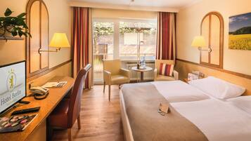 A hotel room with a bed, desk, chair, and a view of the outdoors.
