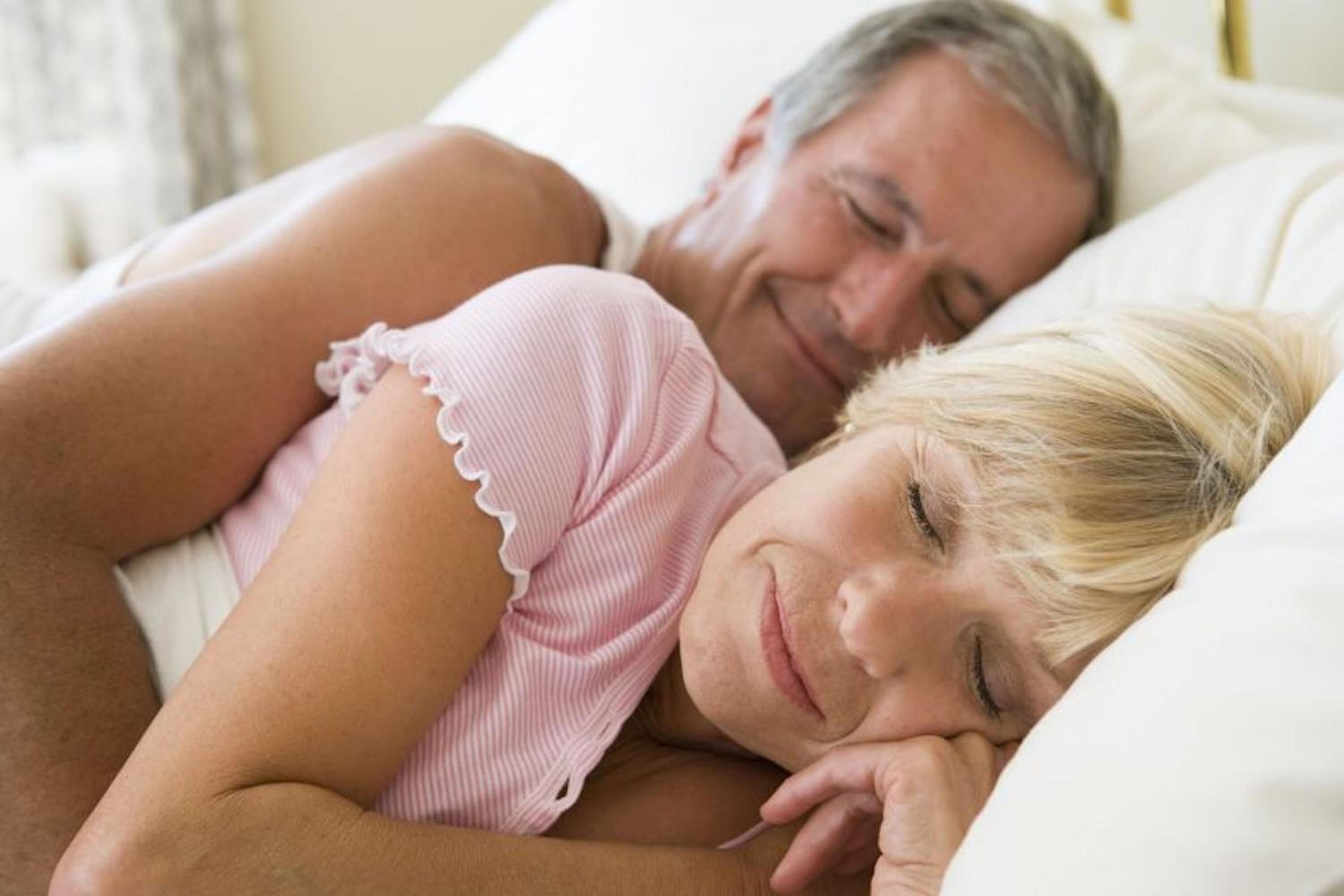 Una persona acostada en la cama con un almohadón.