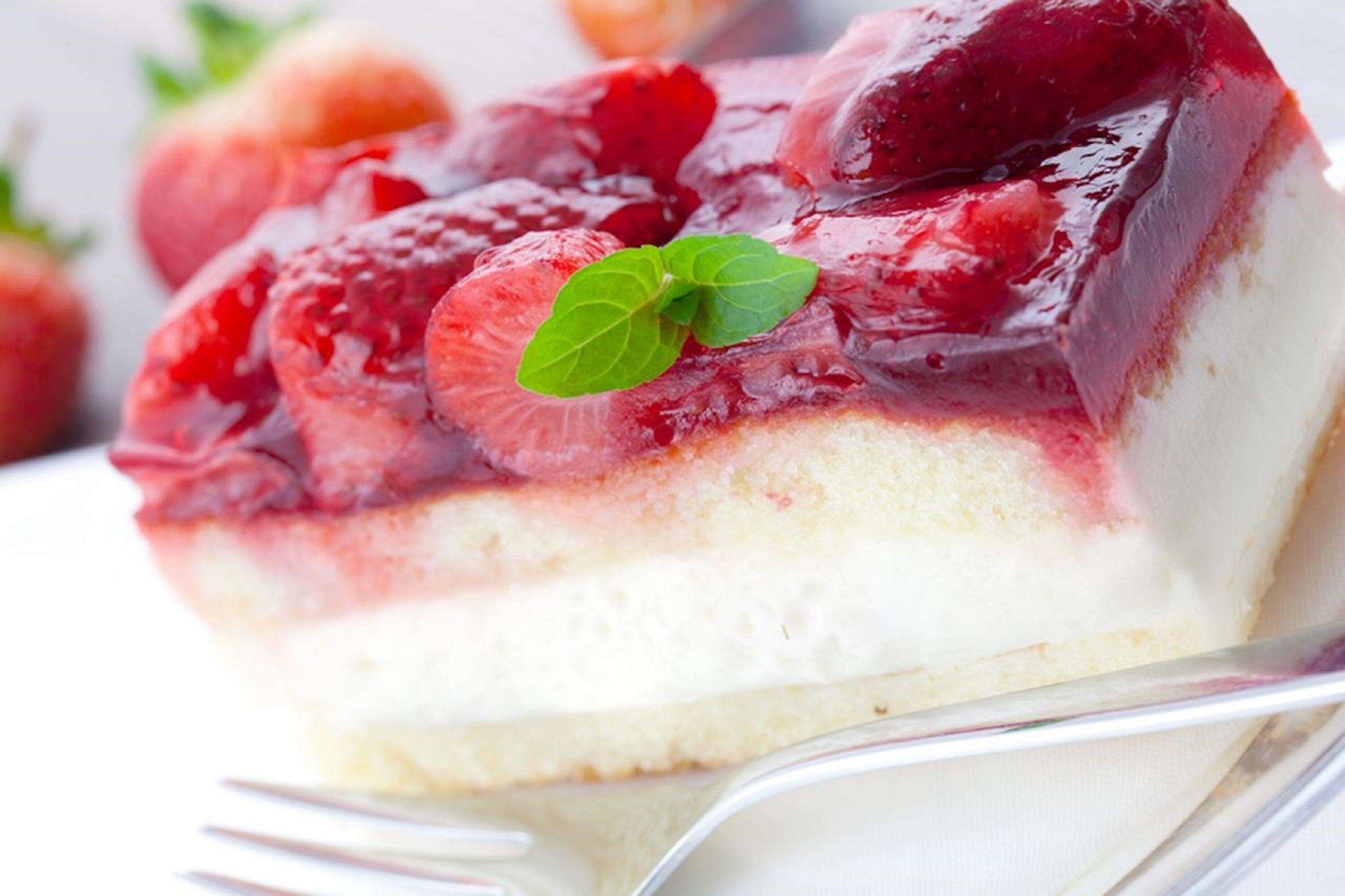 Una porción de postre en capas con fresas y una hoja de menta como decoración.