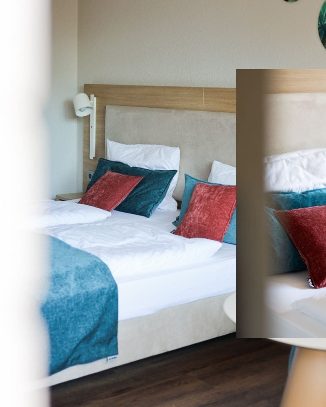 Una cama bien hecha con sábanas blancas, un cabecero de madera y varios almohadones en rojo, azul y verde azulado.