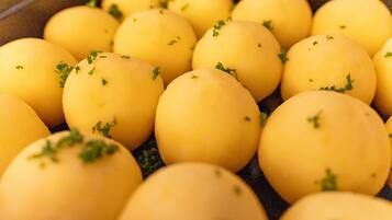 Nahaufnahme von einigen gelben Kartoffeln, verziert mit grünen Kräutern.