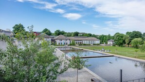 A serene outdoor area with a reflective pool, surrounded by greenery and modern buildings. - Hotel Thüringenschanze (Oberhof)