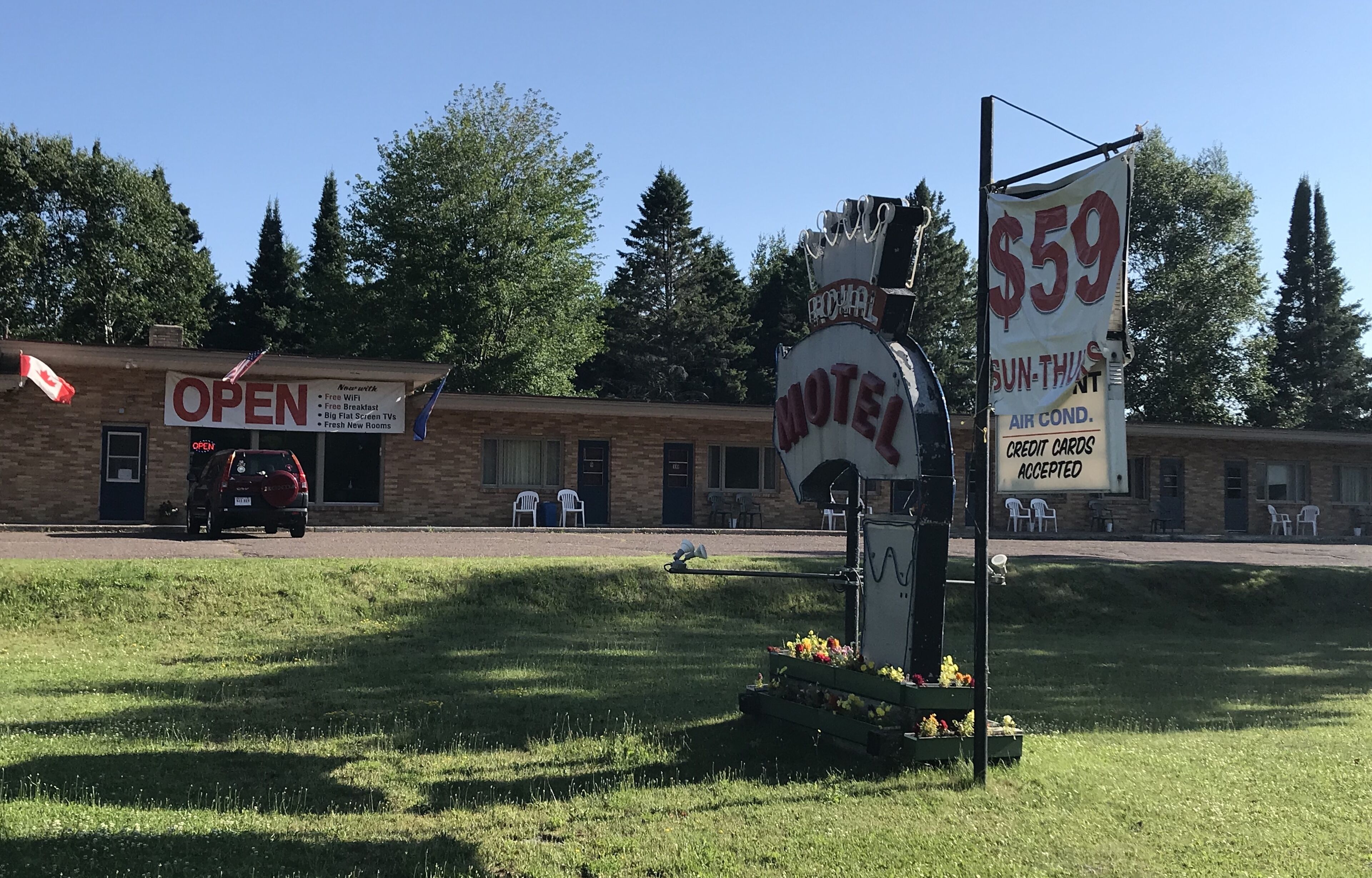 Un motel con un letrero que anuncia habitaciones a 59 dólares, WiFi gratuito y aire acondicionado.