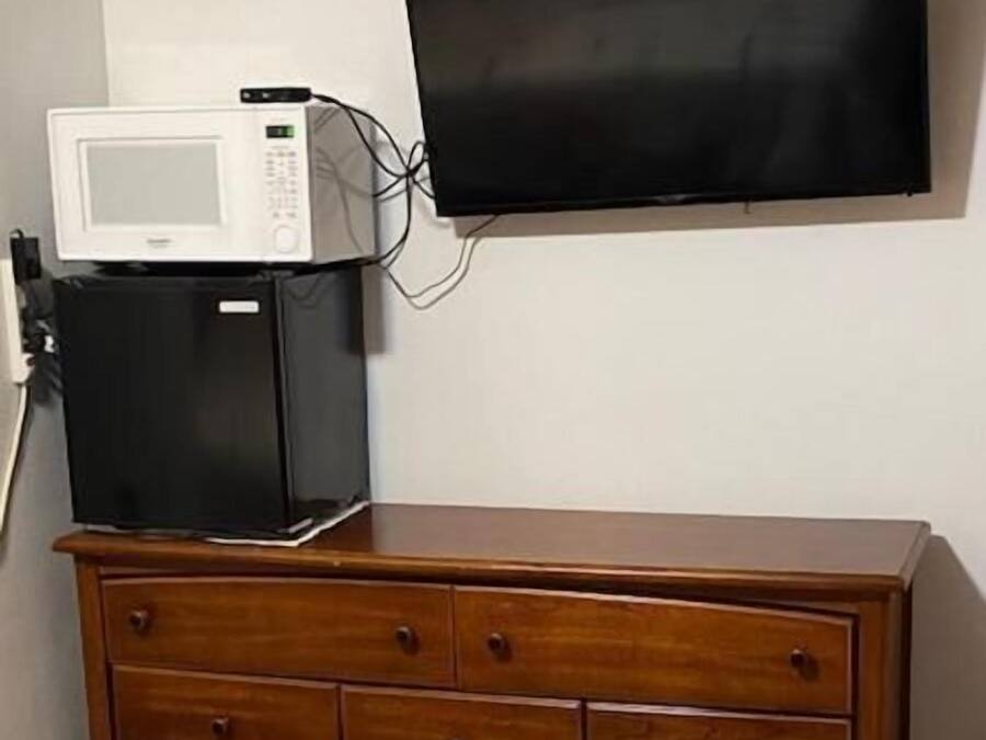 A wooden dresser with drawers and a microwave on top.