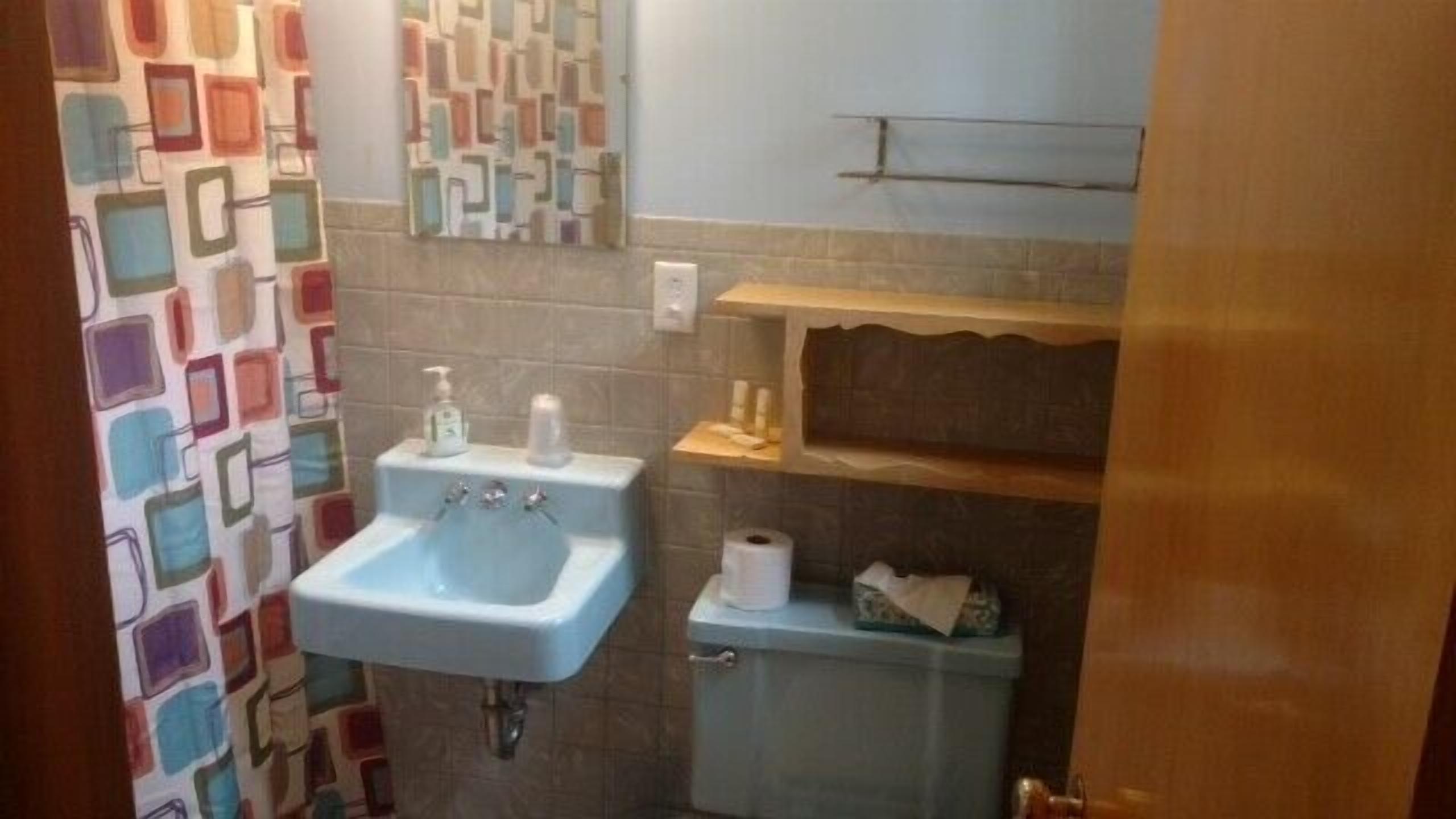 Un baño con lavamanos, inodoro y estante sobre el inodoro.