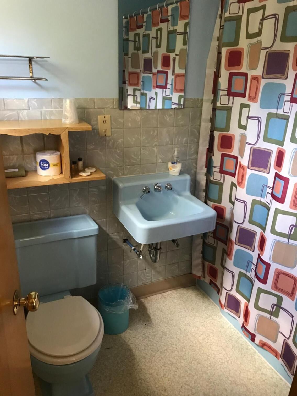 Un baño pequeño con inodoro, lavabo y cortina de ducha con diseño geométrico.