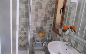 Un bagno con cabina doccia in vetro, un lavandino bianco e uno specchio sopra il lavandino.