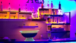 A bar area with shelves of bottles and glasses, a neon sign, and a bar counter. - Ares Dream Hotel- All Inclusive (Kemer)