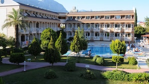 A hotel with multiple balconies, a swimming pool, and a mountainous backdrop. - Ares Dream Hotel- All Inclusive (Kemer)