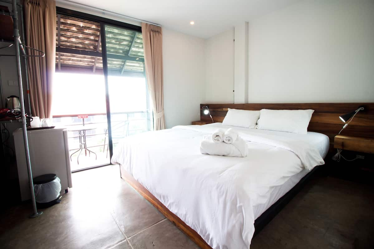 A hotel room with a large bed, a desk with a chair, and a view of the outdoors.