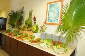 A buffet setup with various dishes and decorative plants.